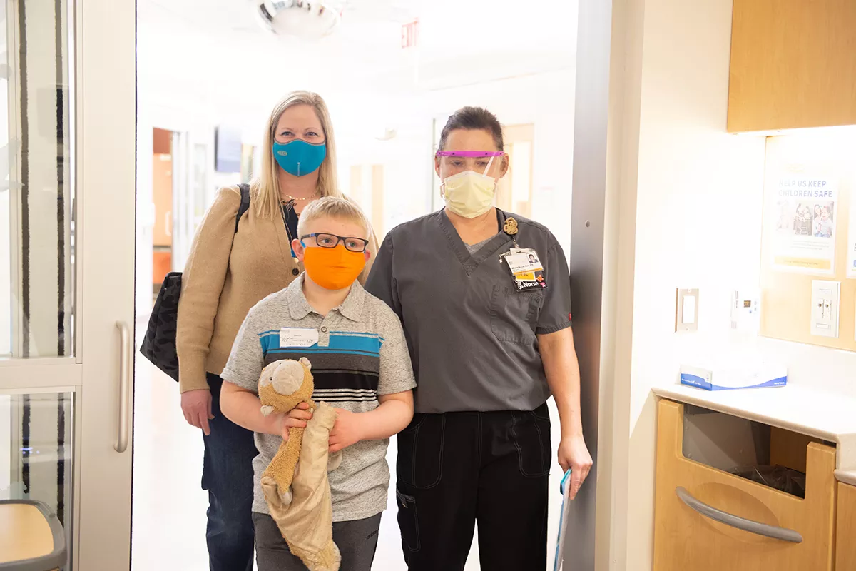 Mother, her child, and nurse enter a hospital room