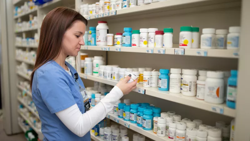 Pharmacy technician selecting different medications from a shelf