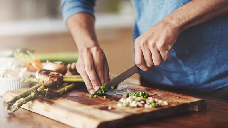 person dicing green onions on cutting board