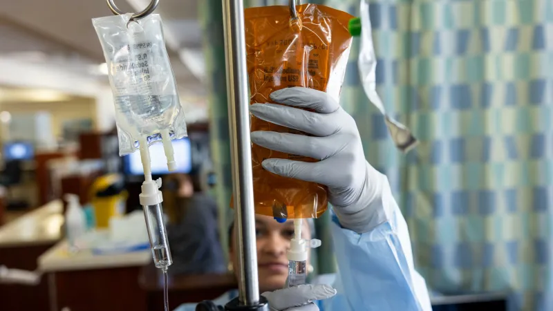 A cancer center nurse sets an infusion bag upon an IV pole.