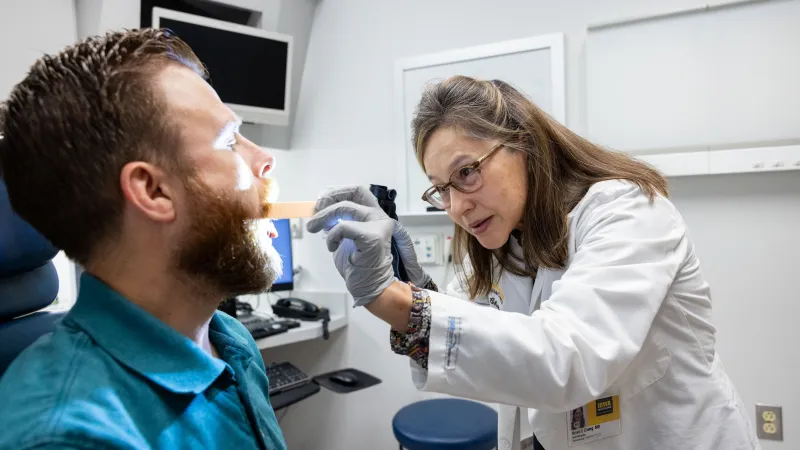 Doctor with adult patient looking in throat