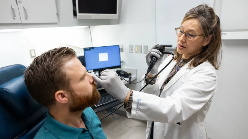 Doctor with adult patient looking in nose