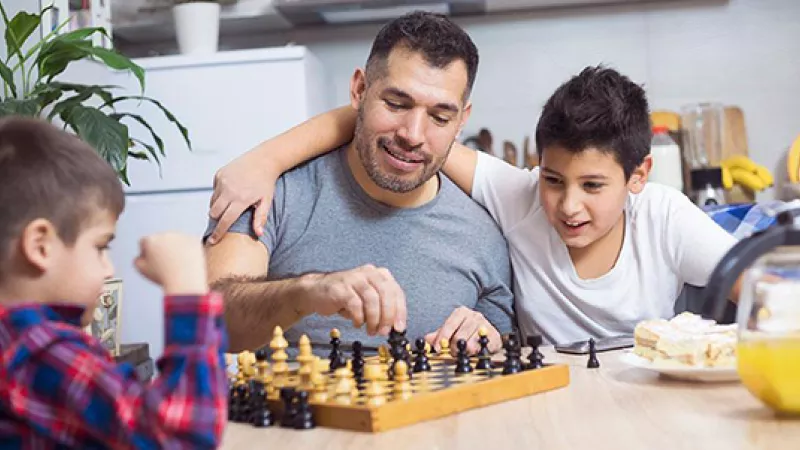 Father and sons playing chess