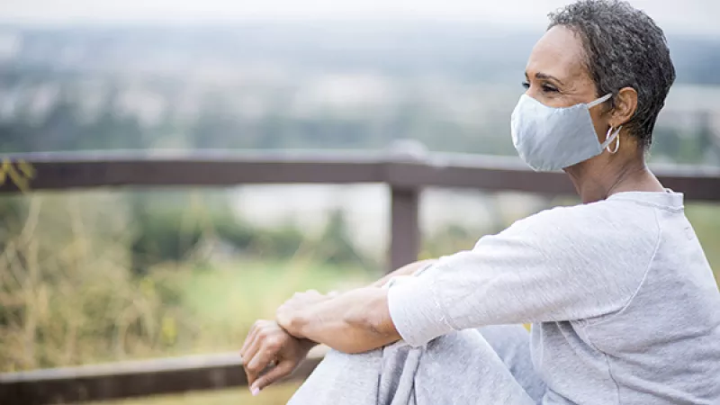 Woman relaxing outside wearing a face mask