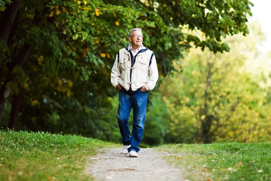 Happy senior man walking and relaxing in park