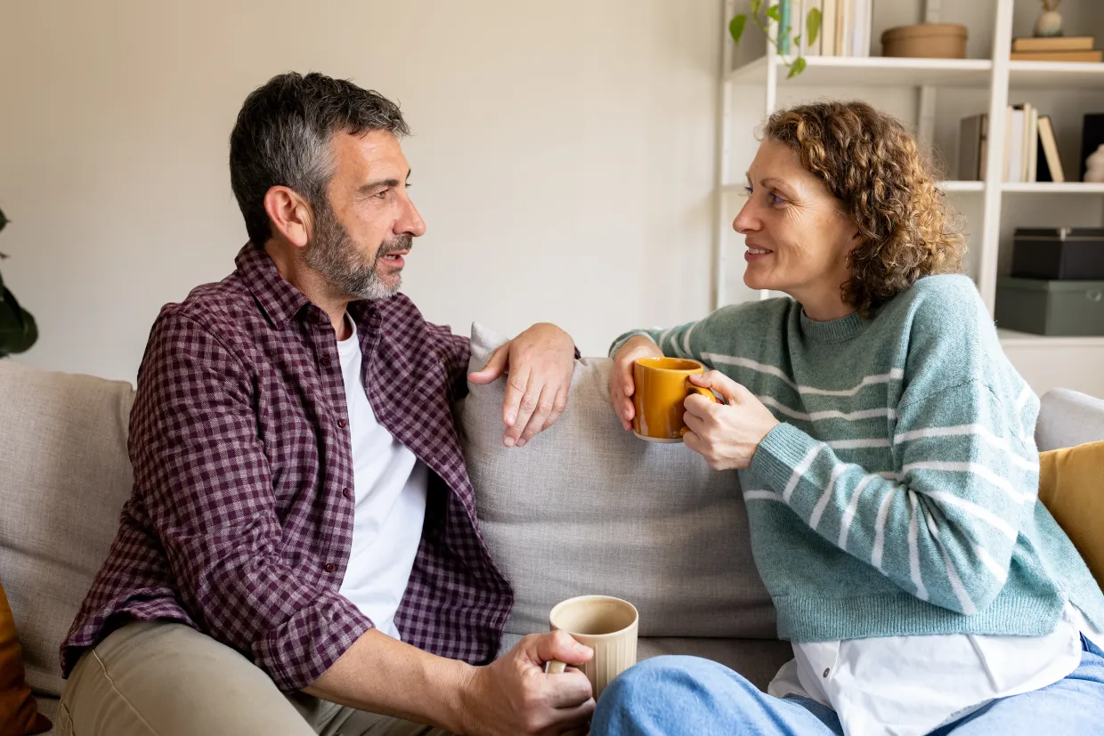 Couple relaxing on sofa at home enjoying coffee and conversation