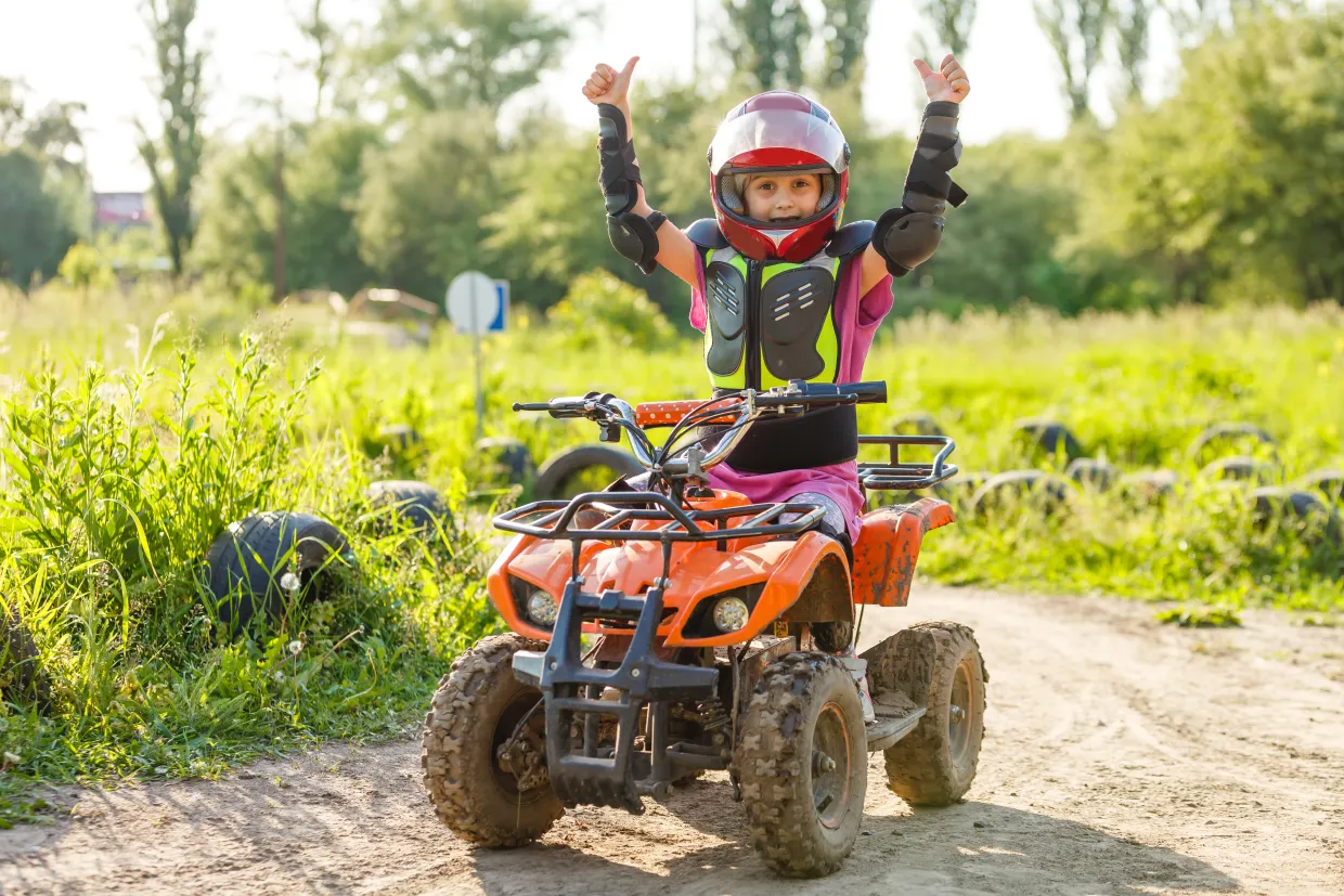 Child riding an ATV with helmet