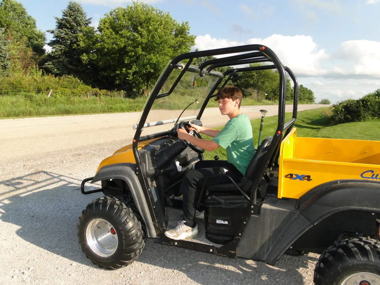Young boy riding an ATV on a gravel road.