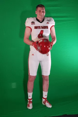 Jacob Remmert poses with his football helmet in front of a green screen
