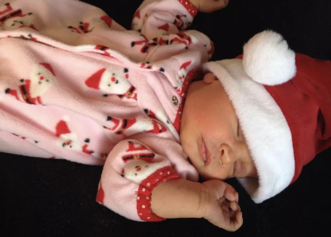 Eve Jimenez as a baby wearing a Santa Claus hat