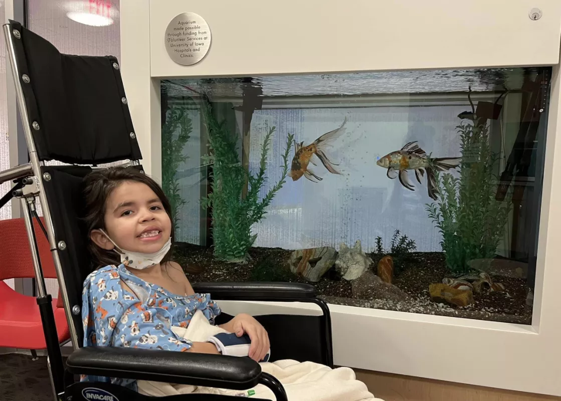 Eve Jimenez sitting in wheelchair in front of fish tank