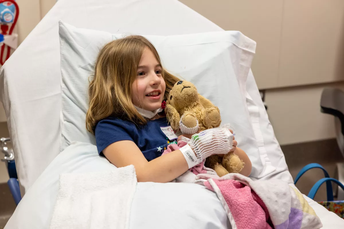 A pediatric patient takes a photo with her stuffed animal, who also has an IV placed in its paw, during preparation for an MRI on Friday, February 24, 2023. Patient consent on file.