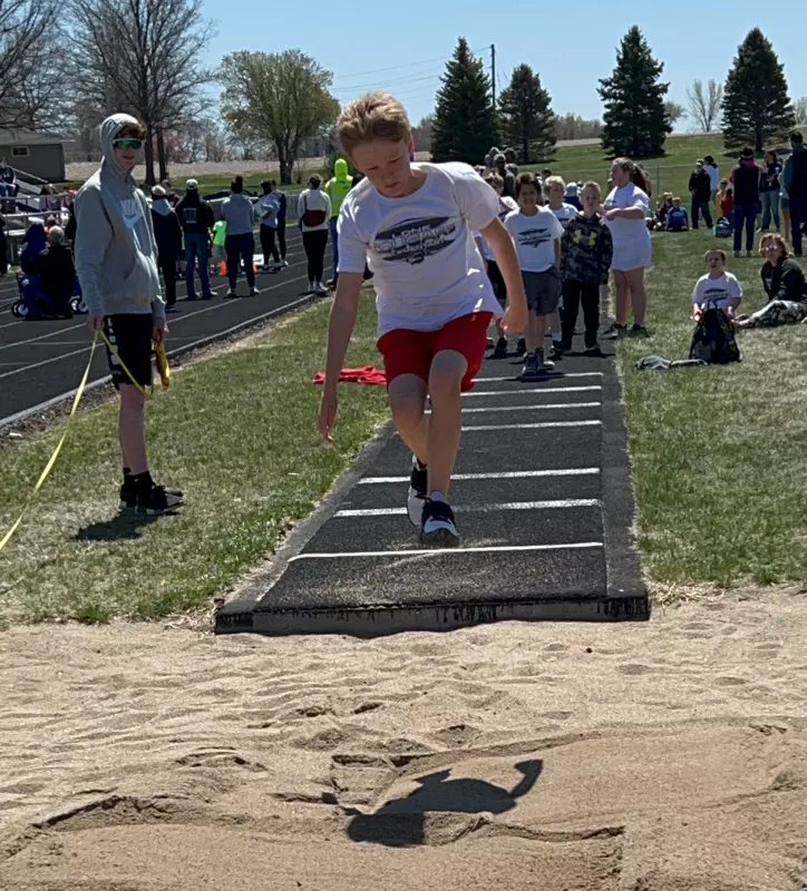 Dutch Hardeman taking a leap into sand during a youth sporting event