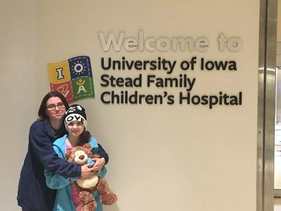 Gabby Ford with her mom in front of Stead Family Children's Hospital sign