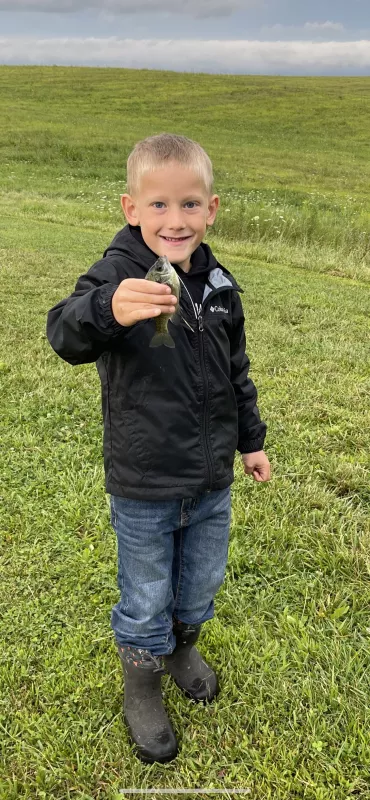 Max Schlee holding a small fish in his hand