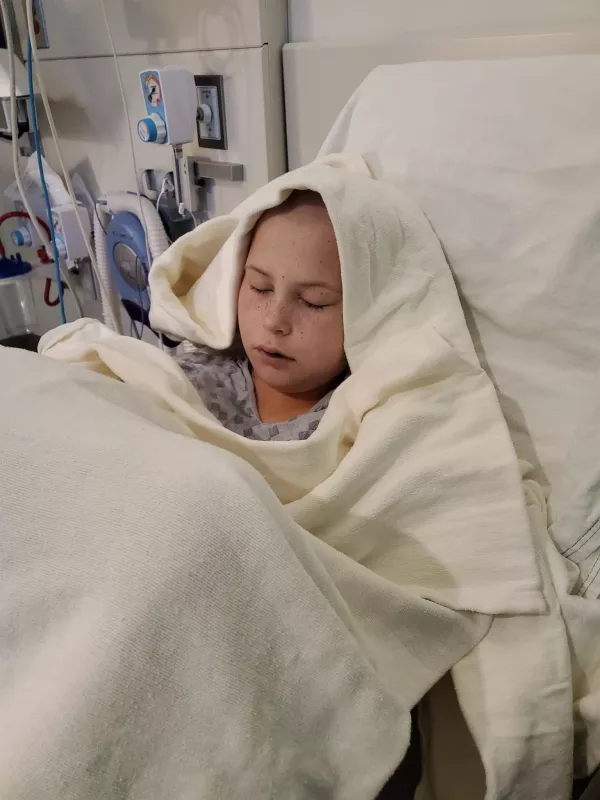 Kid Captain Cooper Estenson sleeping in hospital bed with head wrapped