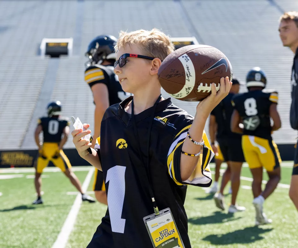 Carter throwing a football at Kids Day on the field