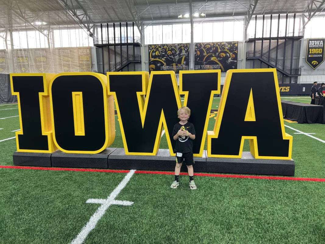 Kid Captain Atlas Coleman standing in front of Iowa Logo