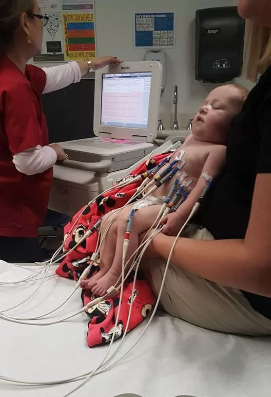 Kid Captain Aiden Washburn in hospital being held by his mother