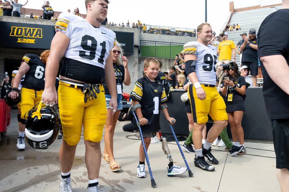 Kid Captain Nolan Stevenson and Iowa football players walk out to cheering fans during Kids' Day.