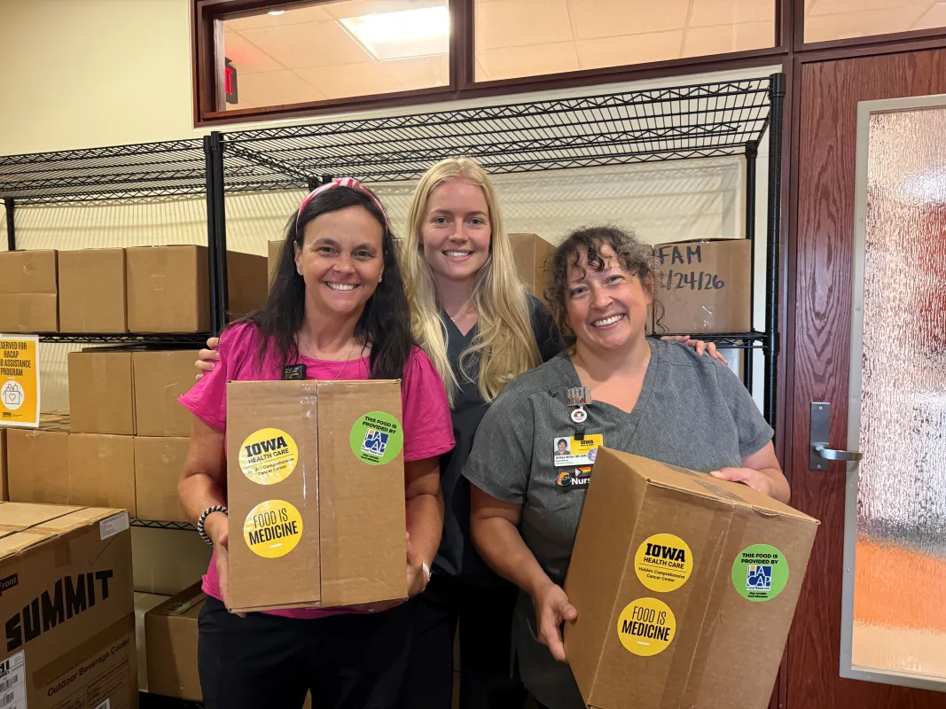 Three people pose with boxes of donated food 