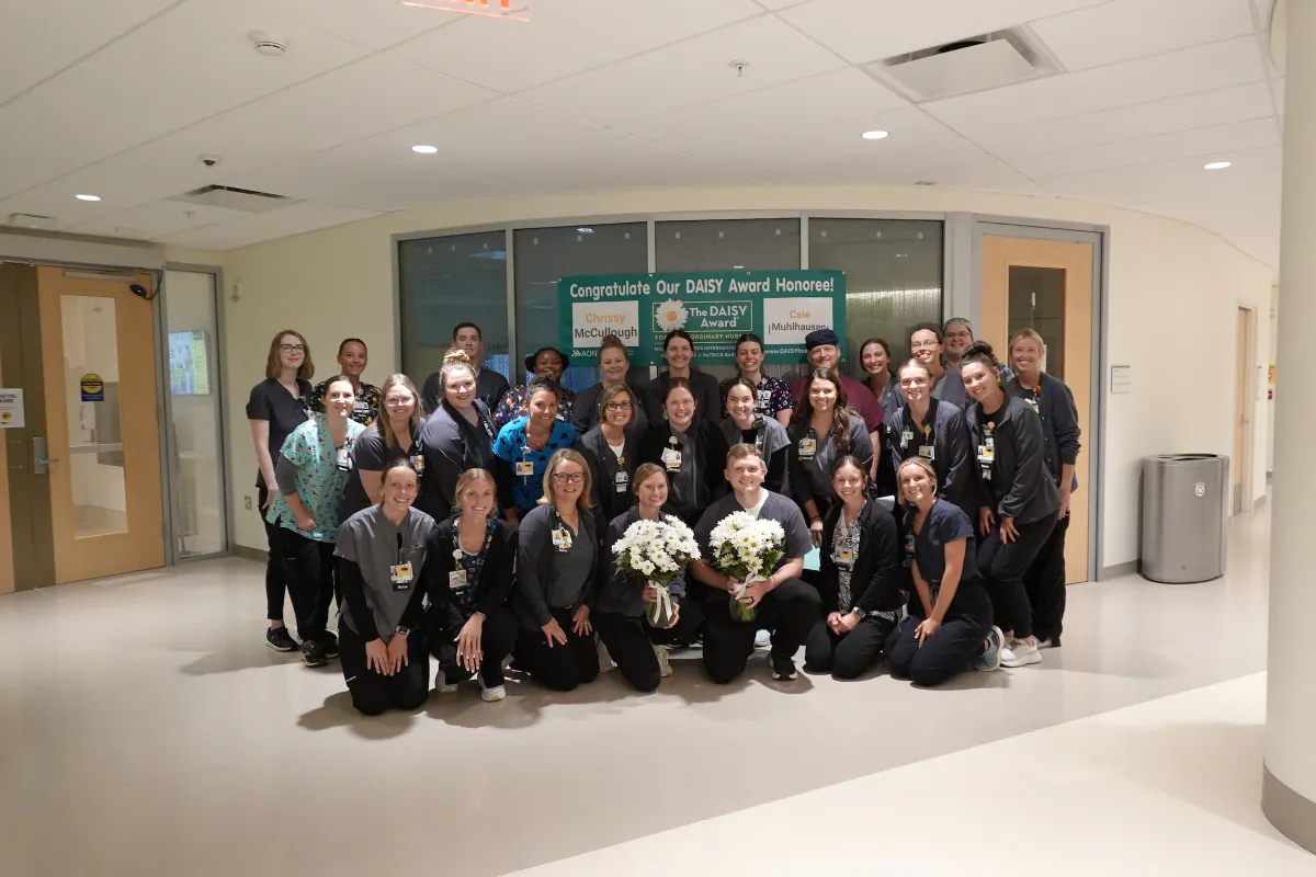 McCullough and Muhlhausen stand center with daisy flowers amongst other members of the PICU team.