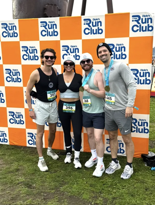 Bailey Cocklin and three friends holding medals after completing a running race.