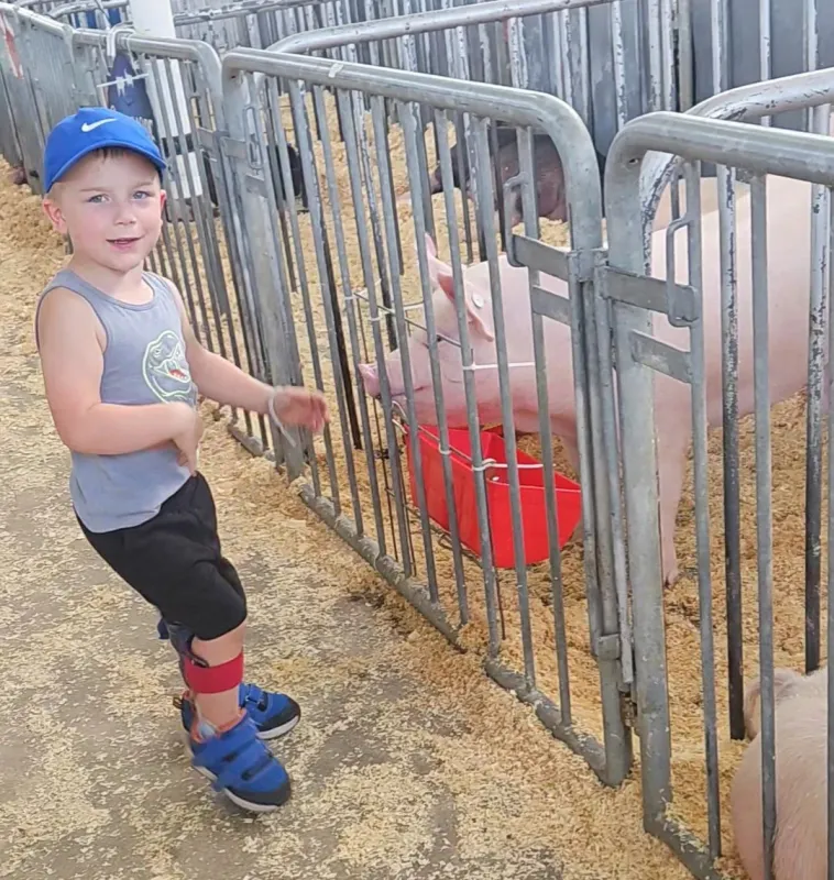 Sawyer Conrad standing next to a pig at a farm