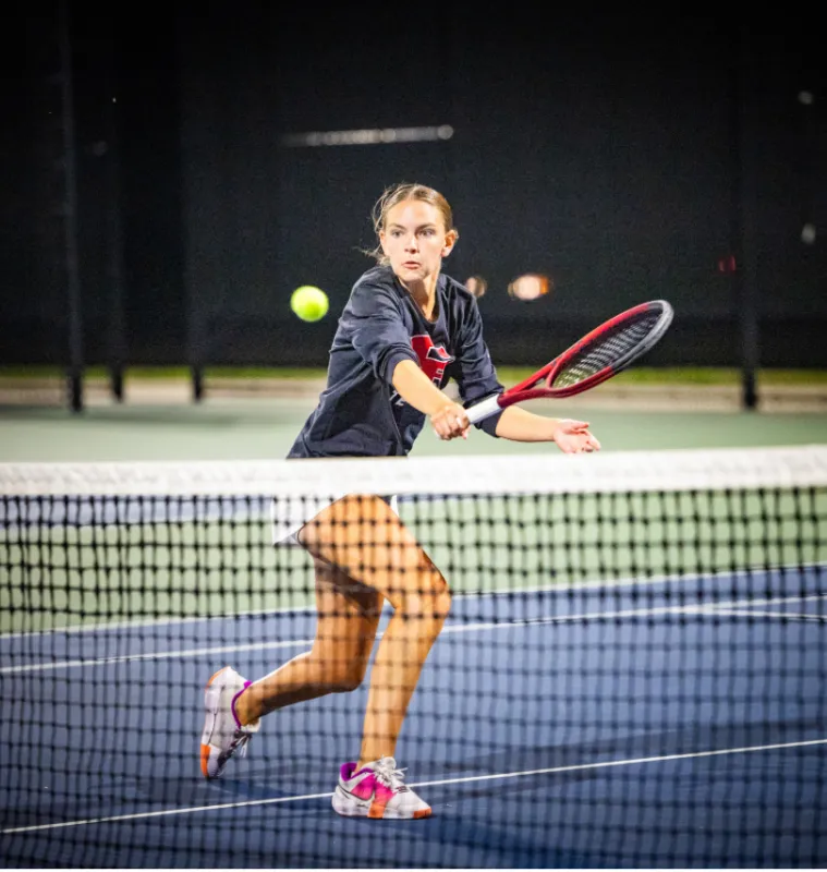 Mackenzie Sagers bending low to volley a tennis ball