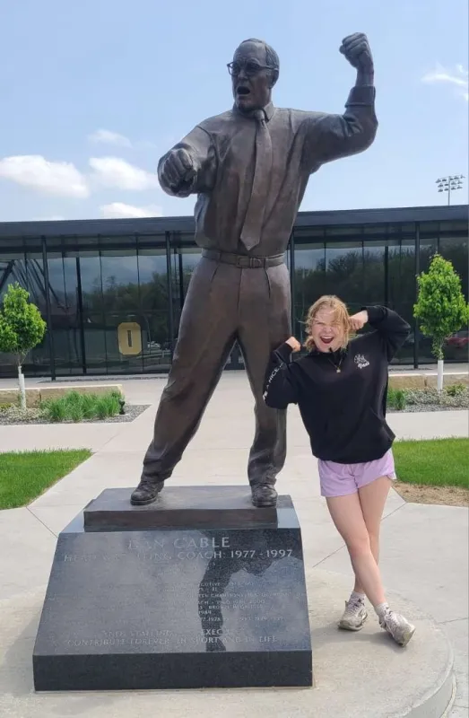 Keisha Tomac poses with Dan Gable statue outside Carver Hawkeye Arena