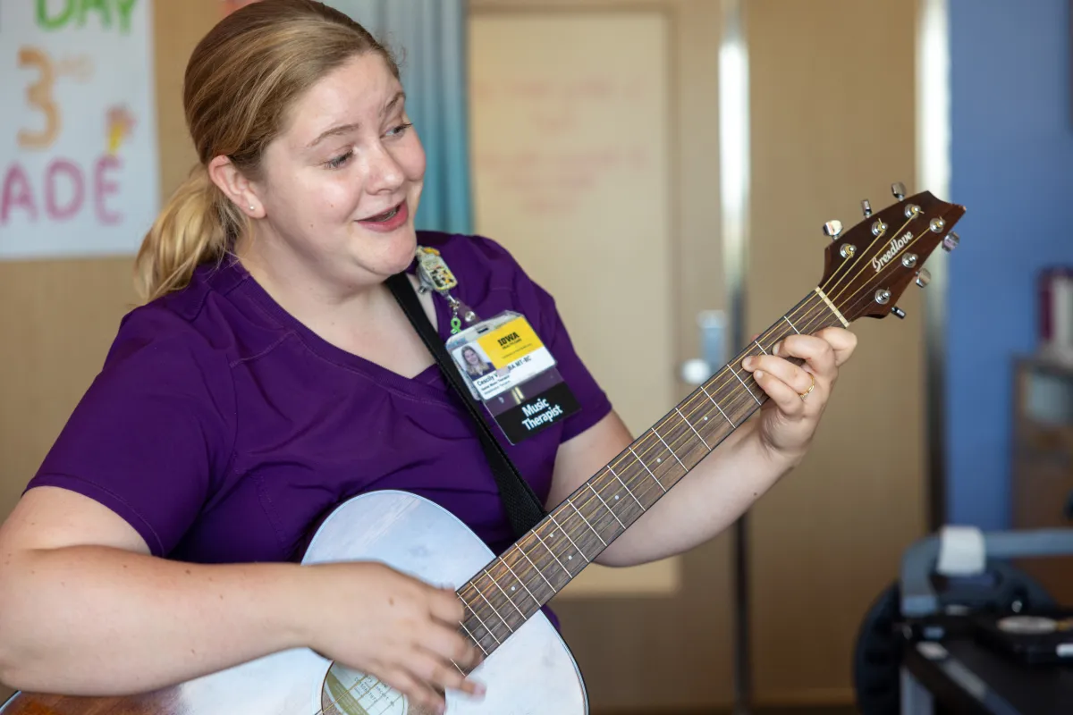 Image of a Music Therapist singing to a patient