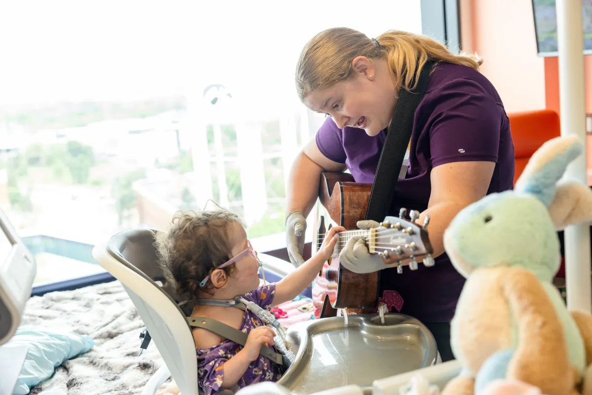 Image of a Music Therapist singing to a patient