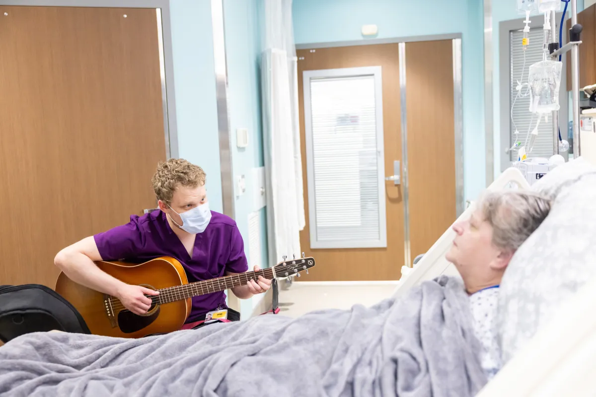 Image of a Music Therapist singing to a patient