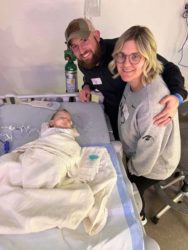 Bodhi in a hospital bed with his parents watching from the bedside.