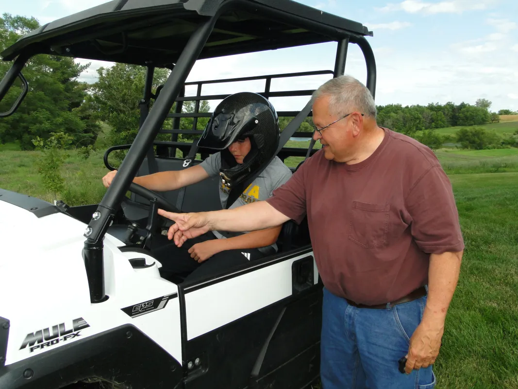 Man with young child pointing inside an UTV