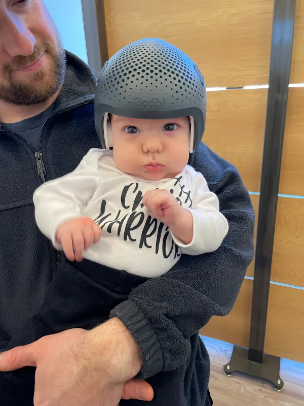 Bodhi wearing his helmet while being held by his dad.