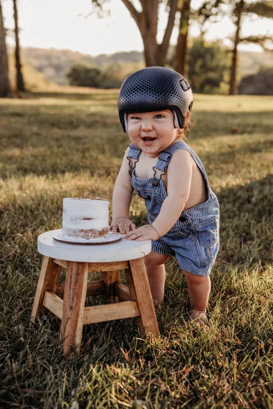 Bodhi smiling while eating a cake outside.