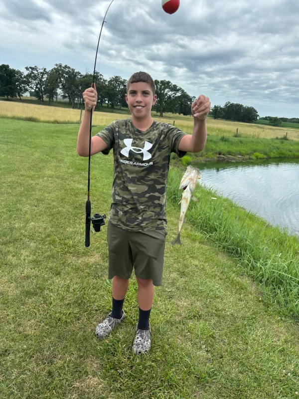 Kid Captain Beau Harvey holding a caught fish and fishing rod