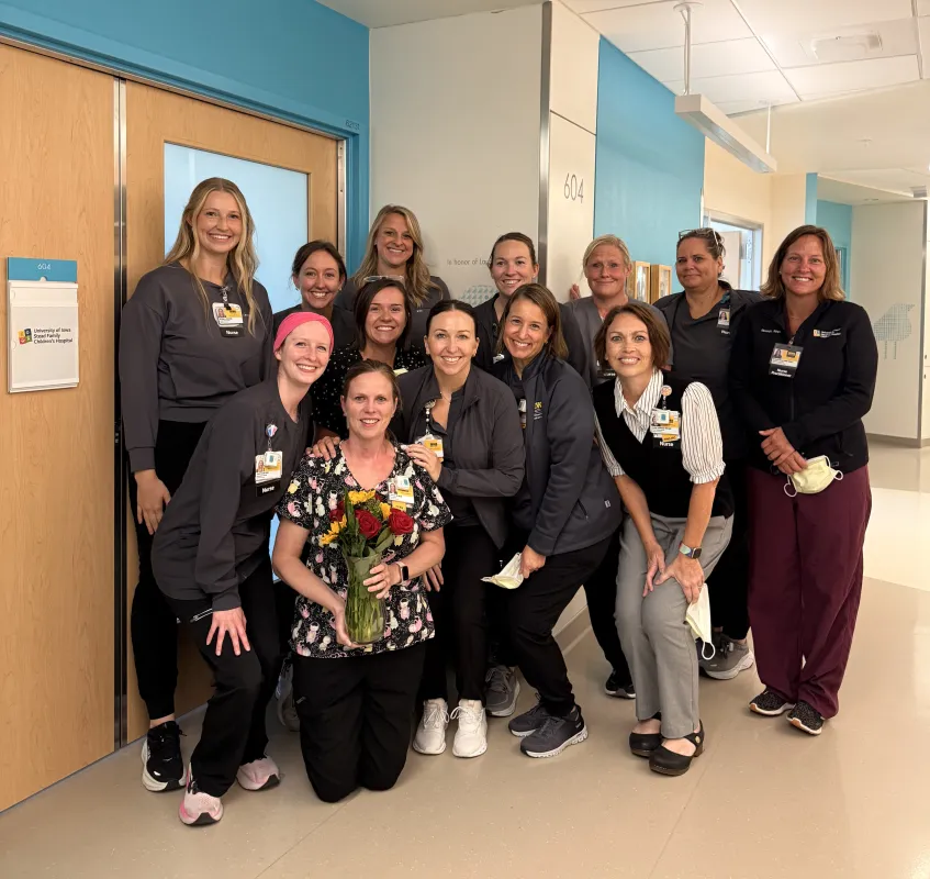 Laura Corbett, center, poses with nurses from her neonatal intensive care unit team who gathered to surprise her after a patient room was named in her honor at University of Iowa Health Care Stead Family Children’s Hospital. 