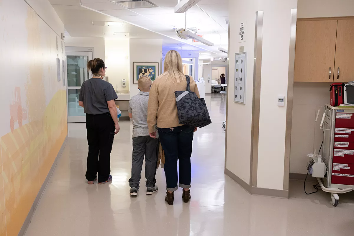 Mother, her child, and the nurse walk down a hallway