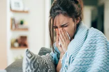 Woman with flu sneezing into a tissue