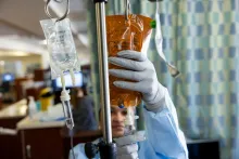 A cancer center nurse sets an infusion bag upon an IV pole.