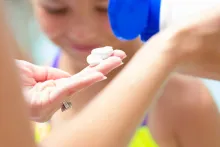 A stock photo of a woman applying sun screen.