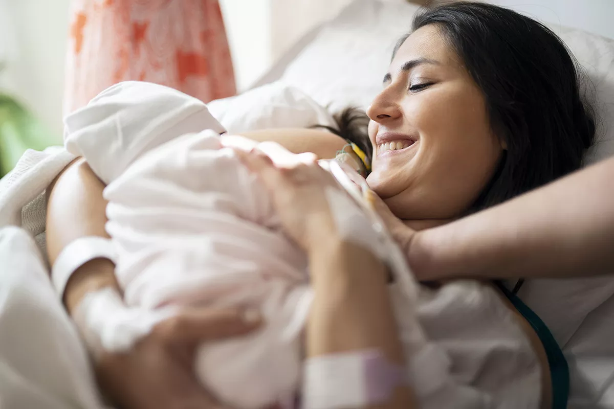Mother holding a newborn baby in her hospital bed
