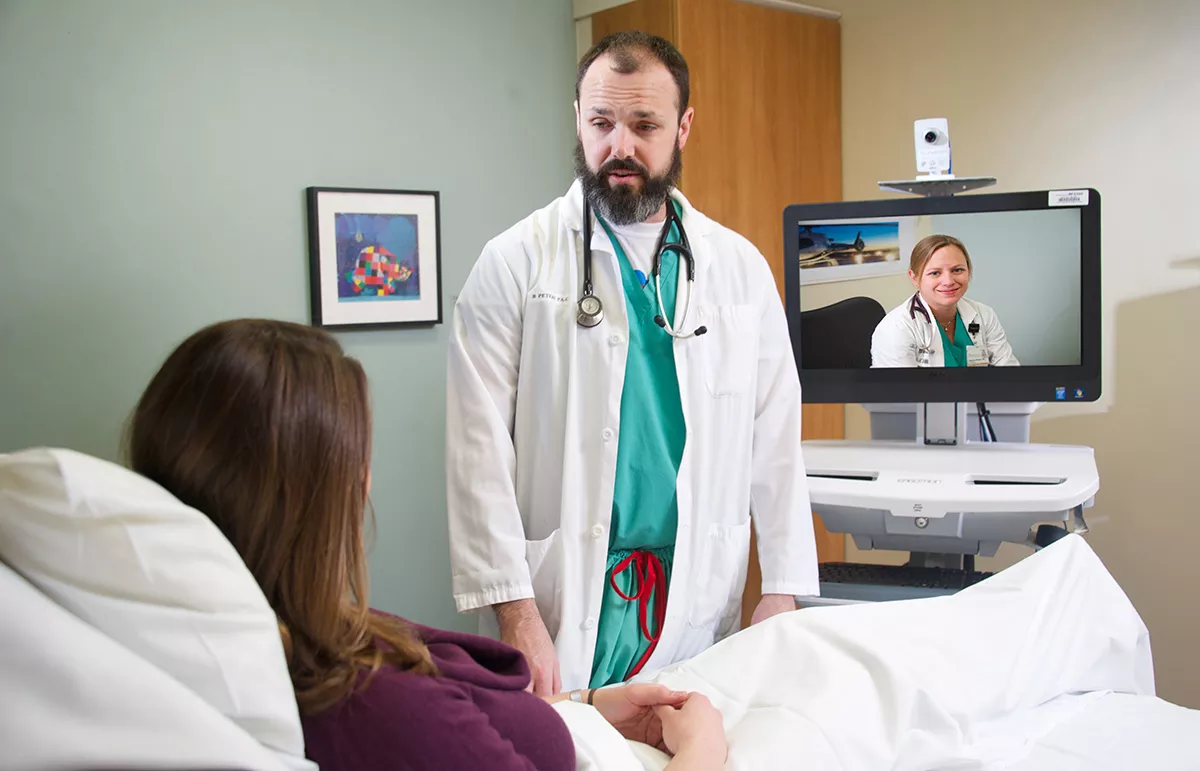 Doctor with patient and hospitalist observing through computer