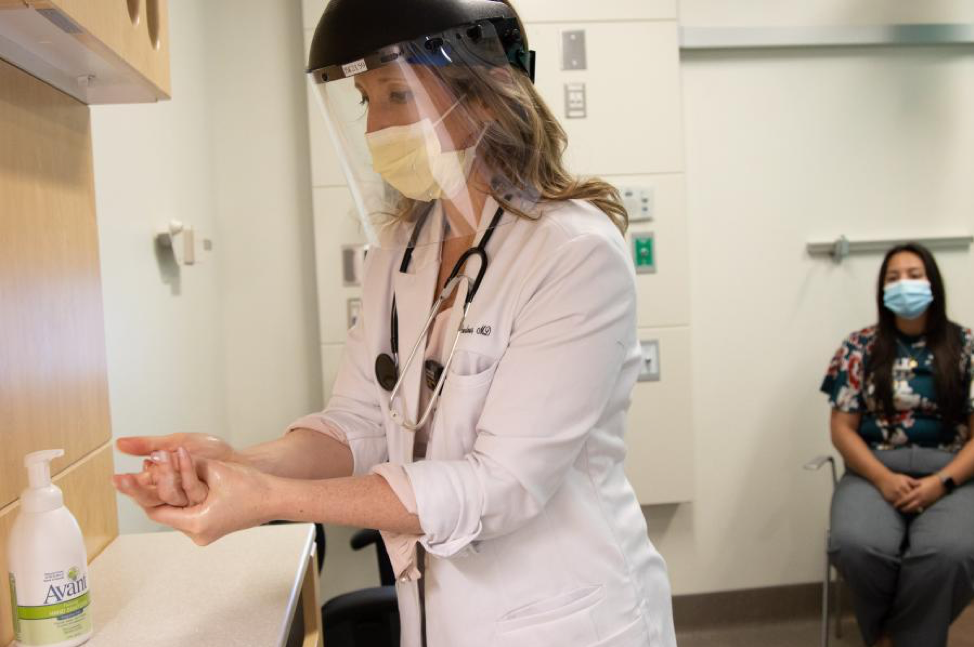 A provider at UI Health Care sanitizes their hands before interacting with a patient 